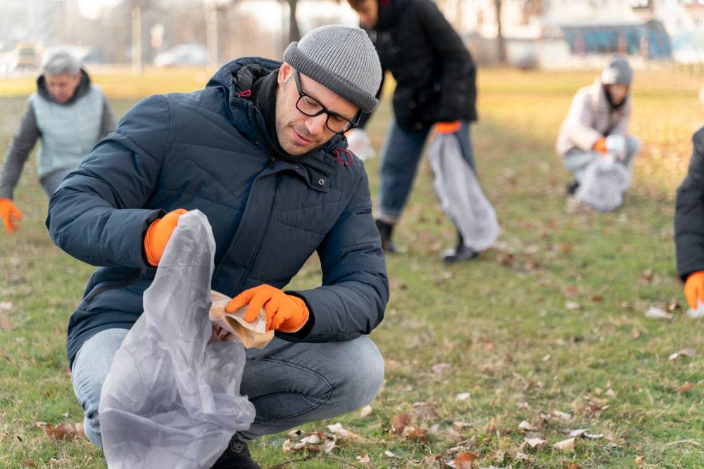 Man volunteering for park cleanup during autumn season.