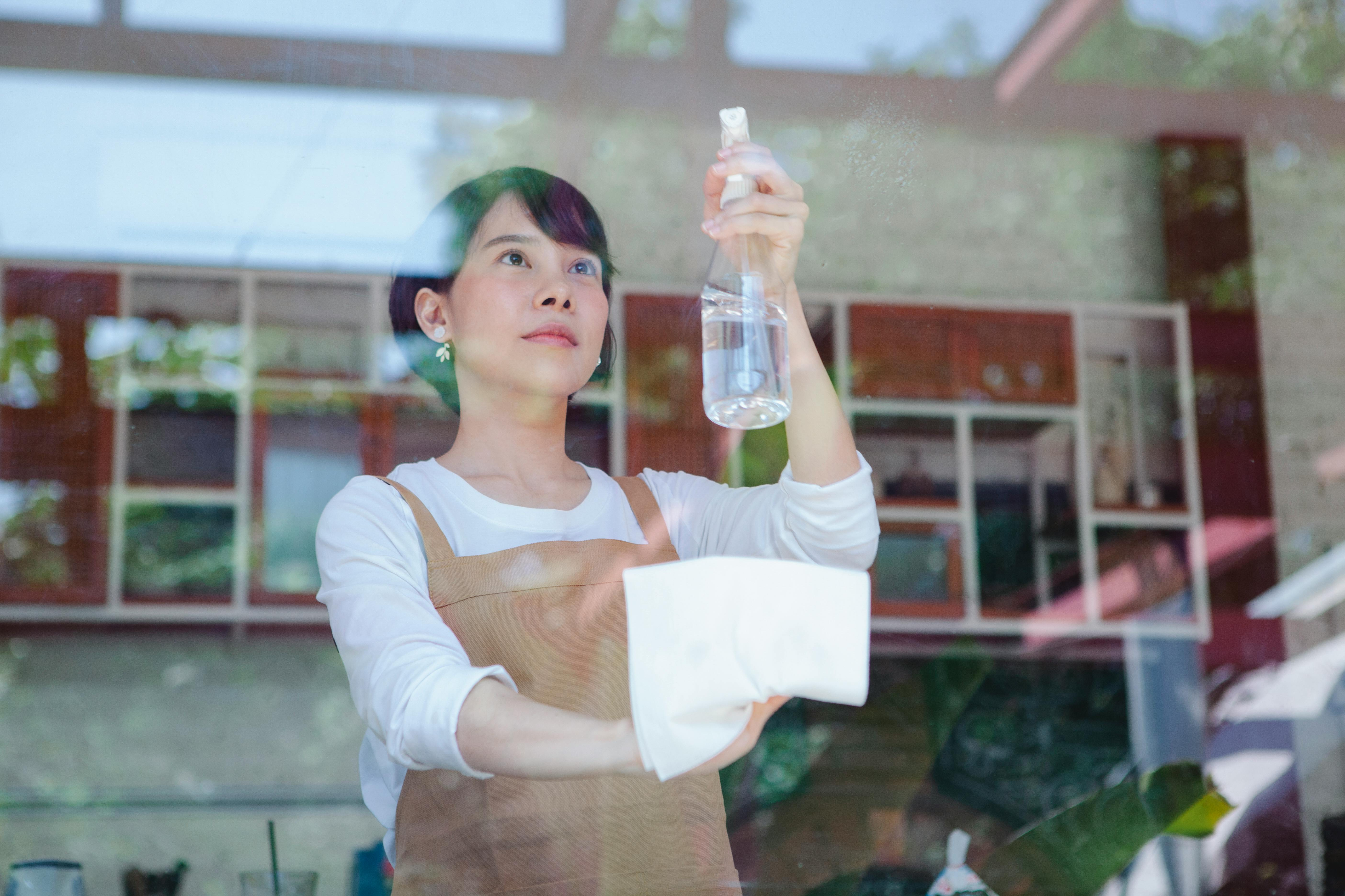 lady cleaning the glass window with a spray cleaning solution