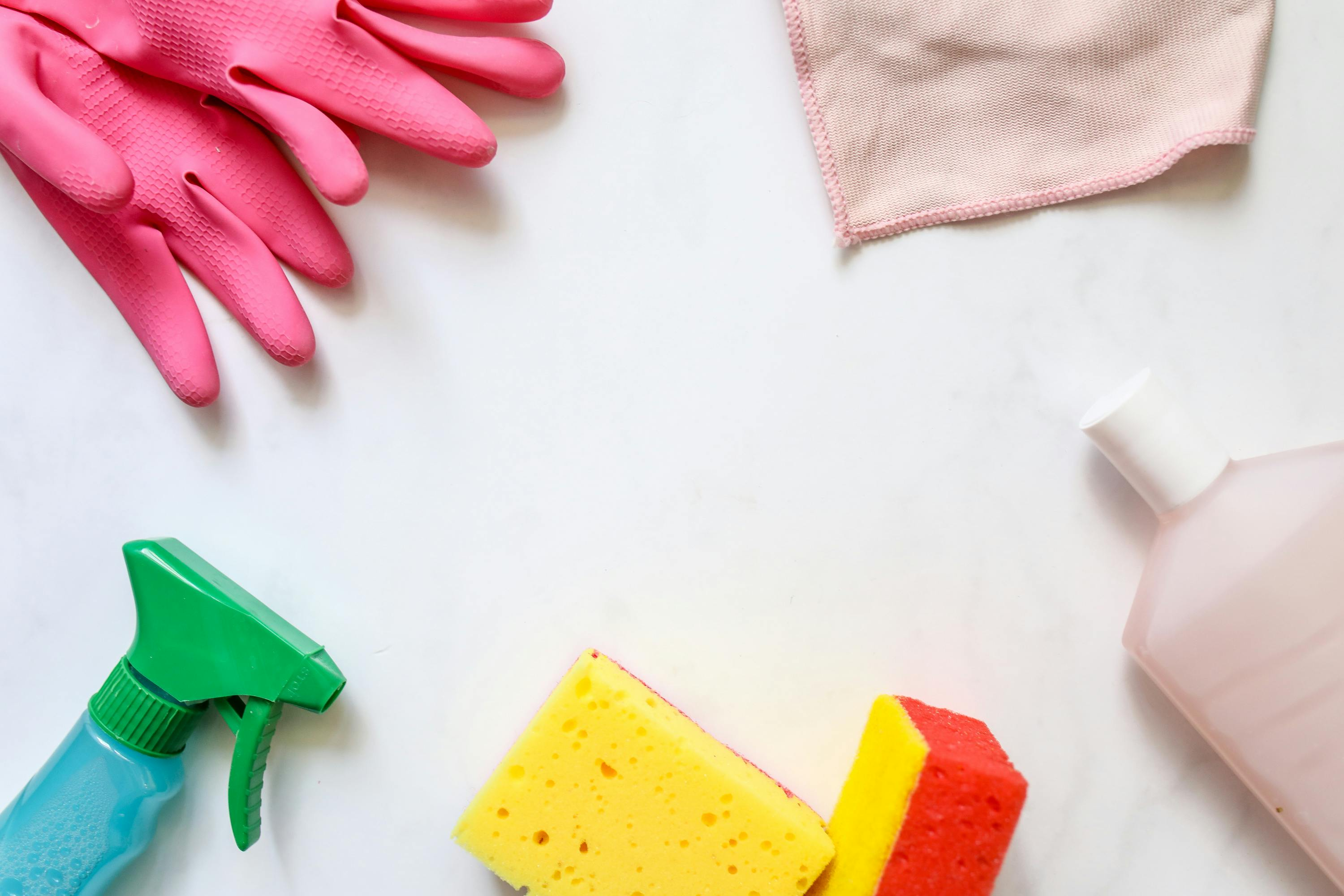 An assortment of cleaning tools like gloves, a spray bottle, a yellow sponge, a cleaning cloth