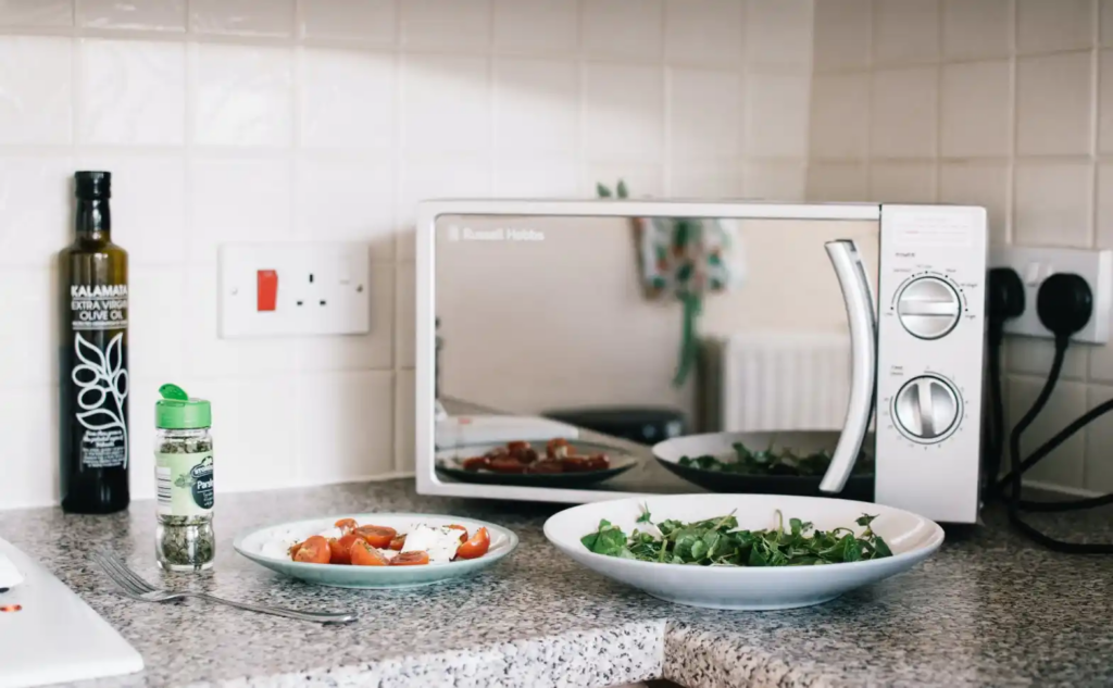 A microwave oven with plates of food in front